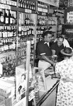 Joe Louis behind the counter serving customers at a liquor store by Harold Hargis