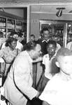 Joe Louis standing with a crowd of onlookers at a liquor store by Harold Hargis