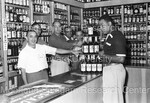 Joe Louis pointing at bottles of Joe Louis Bourbon, 4 other men point to bottles of Joe Louis Bourbon by Harold Hargis