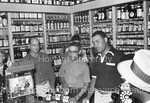Joe Louis standing behind the counter of liquor store while employee holds bottle of Joe Louis Bourbon by Harold Hargis