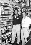 Joe Louis posing with a man behind the counter of a liquor store - 1 by Harold Hargis
