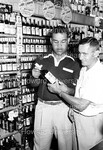 Joe Louis showing a bottle of Joe Louis Bourbon to a patron by Harold Hargis