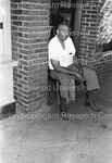 Unidentified man sitting on Coca-Cola crate outside of store by Harold Hargis