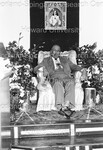 Sweet Daddy Grace seated on stage holding money - 1 by Harold Hargis