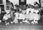 Sweet Daddy Grace seated on stage with 8 umbrella girls standing in front by Harold Hargis