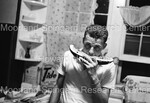Unidentified Man eating watermelon in kitchen by Harold Hargis