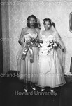 Bridesmaid and Bride standing. Bride holding flowers by Harold Hargis