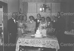 Bride and Groom pose with wedding guest in front od wedding cake by Harold Hargis