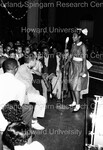 A newly minted member of Delta Sigma Theta standing at the microphone in front of an audience by Hargis Harold