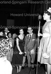 A man and Female Graduate watch a new member of Delta Sigma Theta as she speaks into the microphone by Hargis Harold