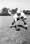Football player in full uniform about to snap a football by Harold Hargis