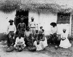 Eleven People Sitting in Front of a House with a Thatched Roof